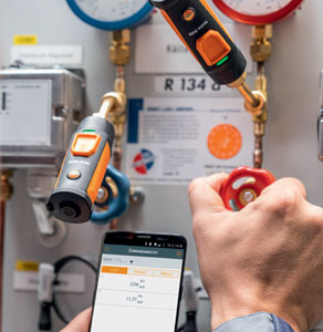 La sonde intelligente 549i de Testo sondant l’étanchéité d’un système de climatisation, par l’entremise d’un téléphone intelligent